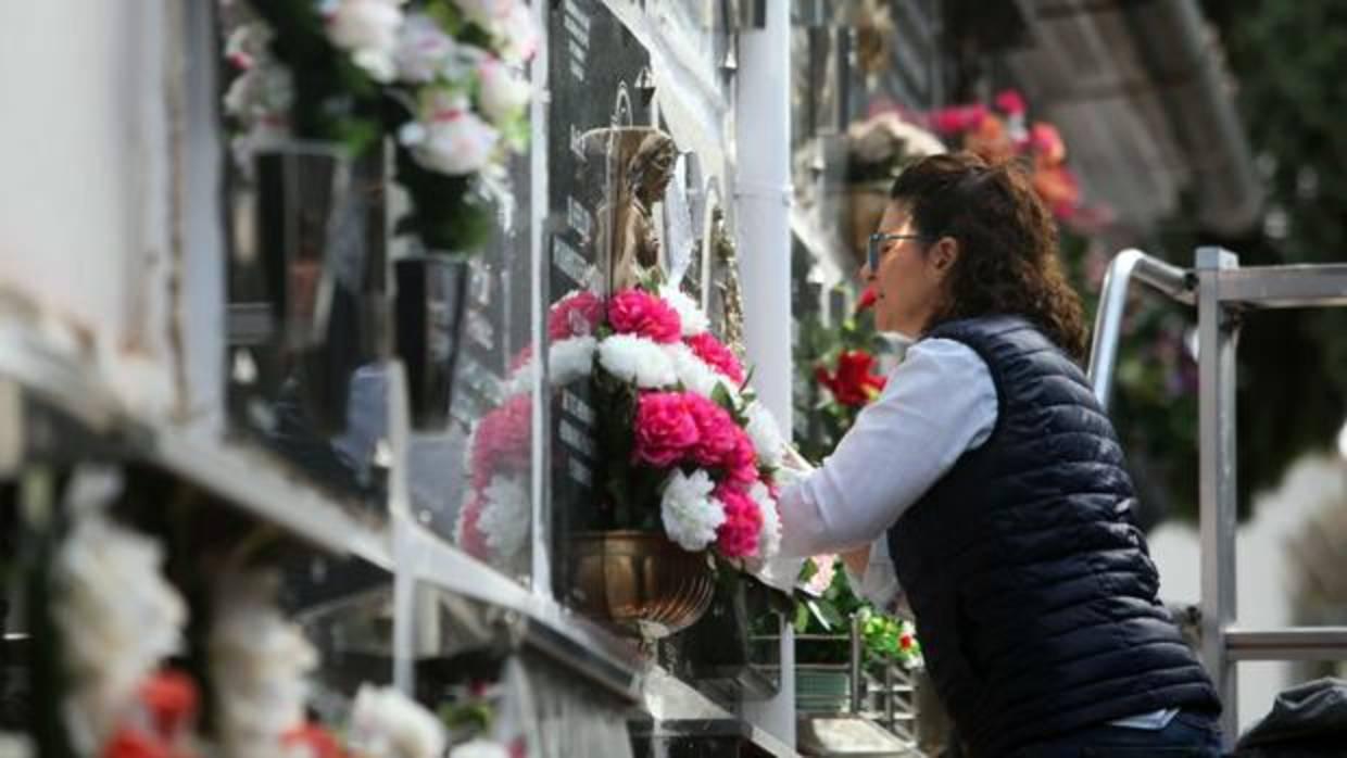 Una mujer adorna la tumba de un familiar en el Día de los Santos