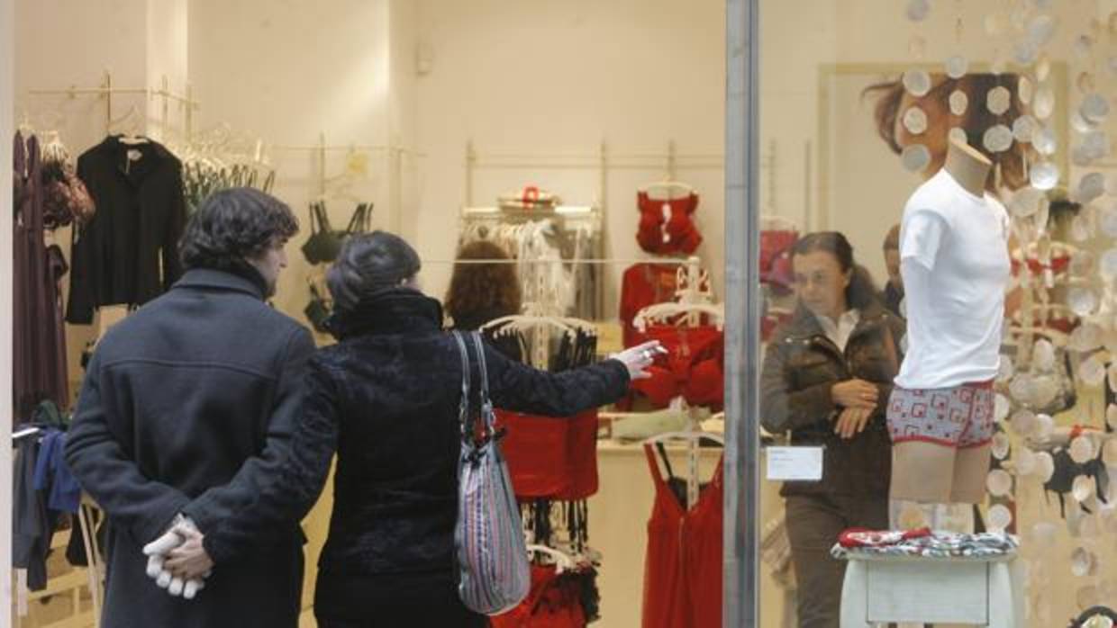 Una pareja observa el escaparate de una tienda de ropa interior del centro de la ciudad