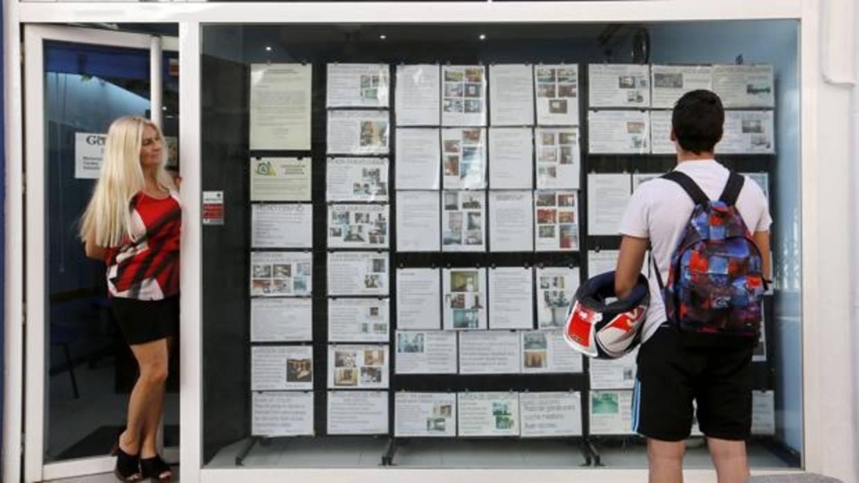 Un joven consulta los carteles de una agencia inmobiliaria