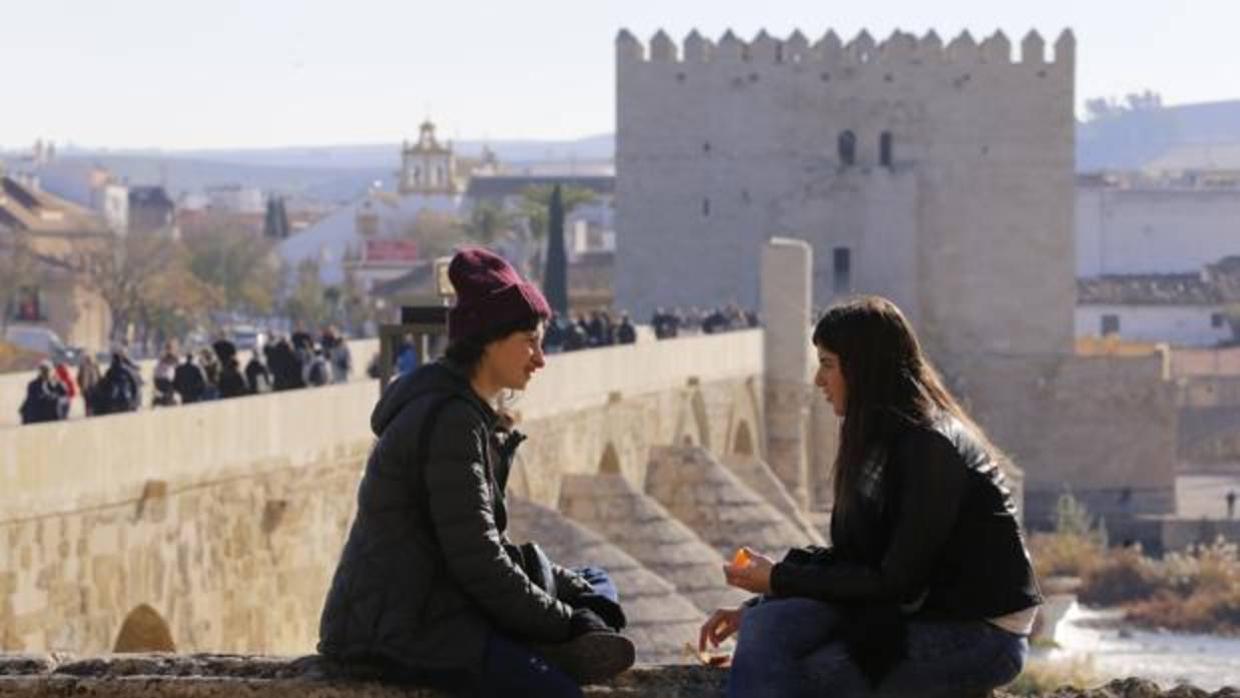 Dos jóvenes descansan al sol, con la Calahorra y el Puente Romano al fondo