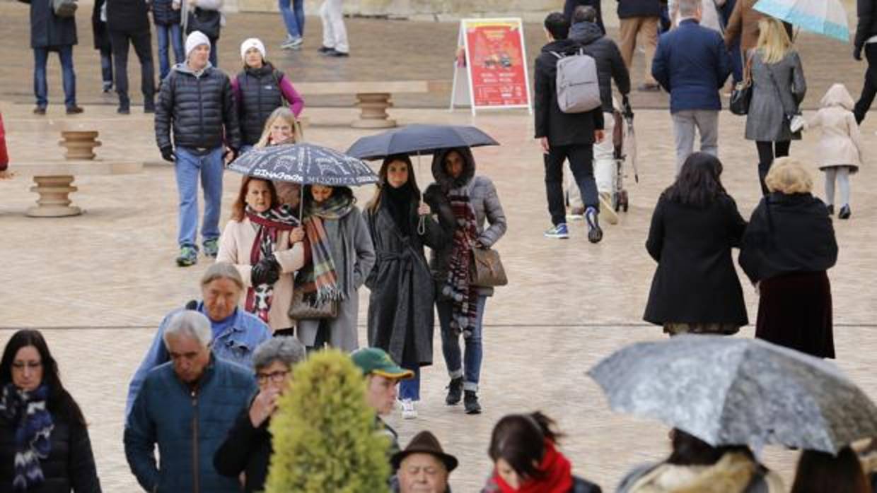 Turistas con paraguas en la zona de la Puerta del Puente de Córdoba