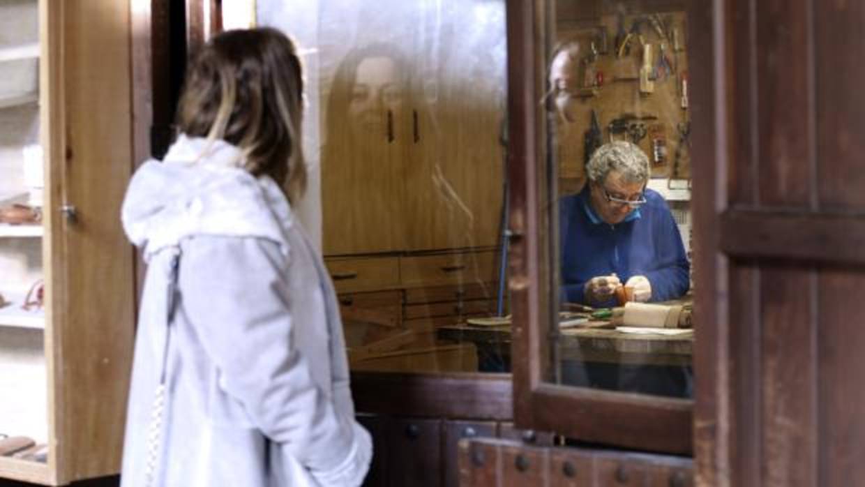 Una turista contempla las labores de un artesano del cuero en el Zoco municipal