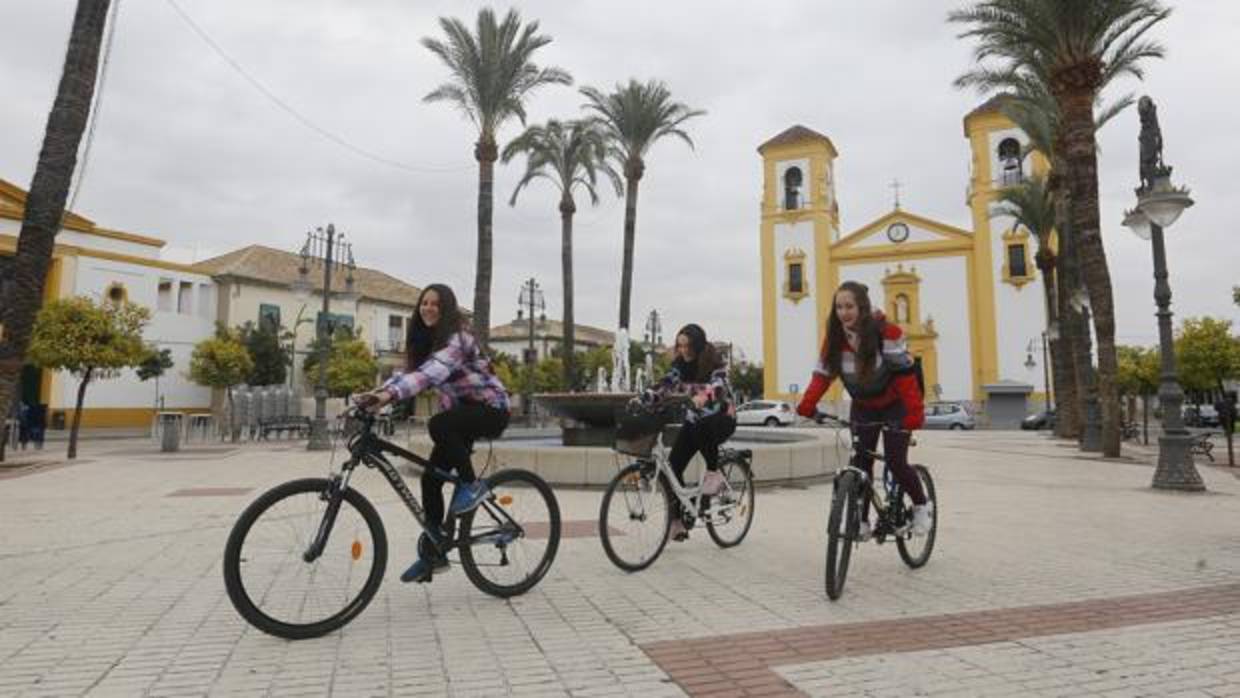 Tres jóvenes en bicicleta por la plaza de Cañero