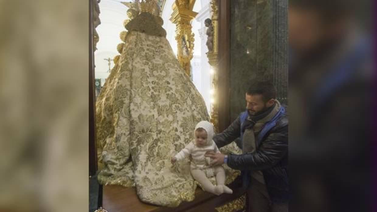 Un niño pasa por el manto de la Virgen