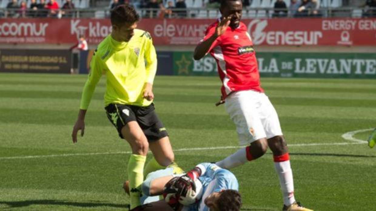 Alberto detiene el balón ante la presencia de Chrisantus en el Real Murcia-Córdoba CF B