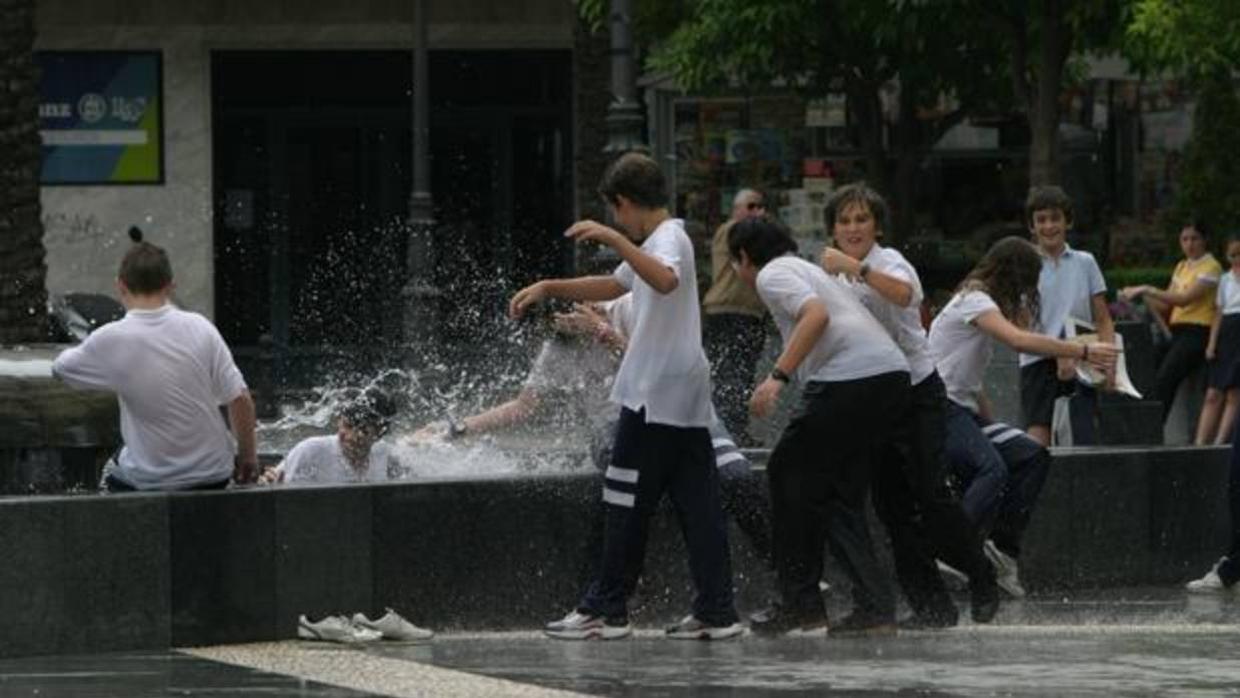 Un grupo de niños se refresca en la fuente de la Plaza de las Tendillas