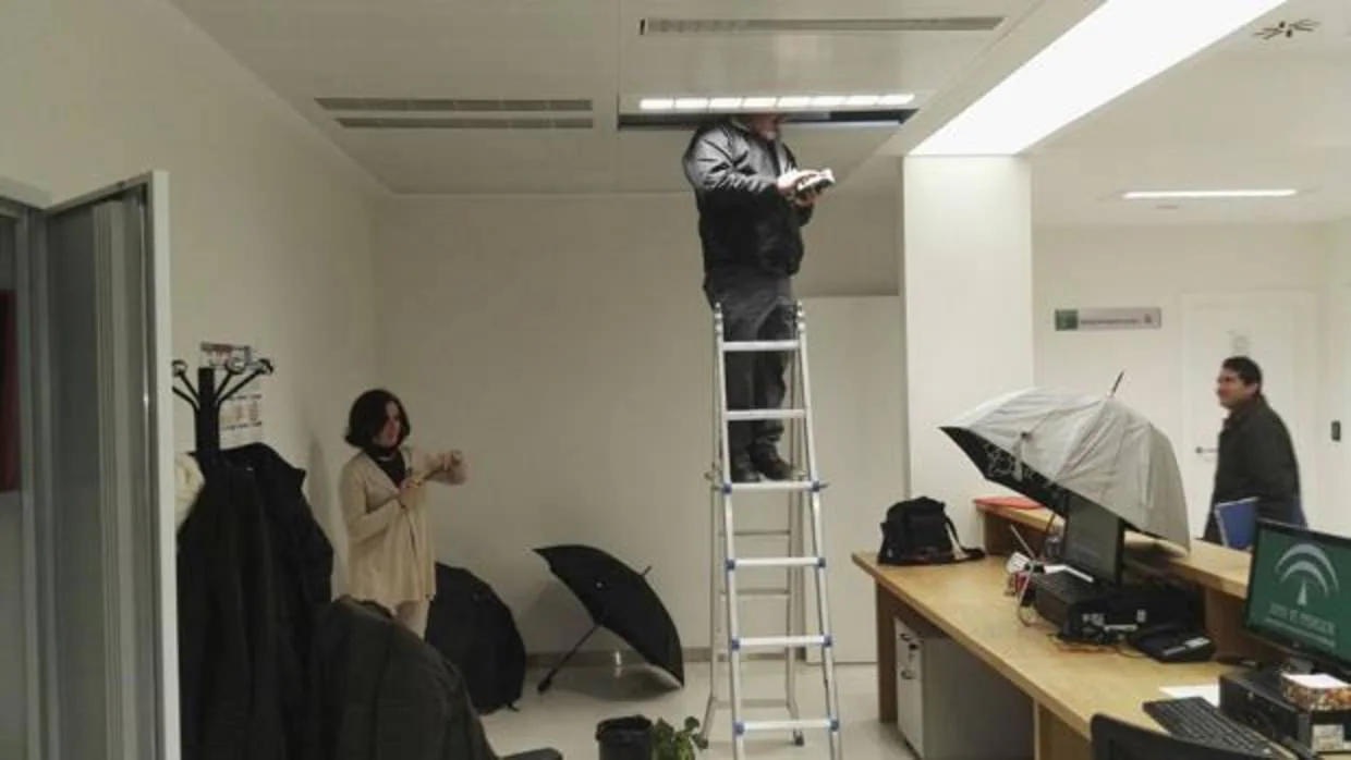Trabajadores fotografían un ordenador protegido con un paraguas
