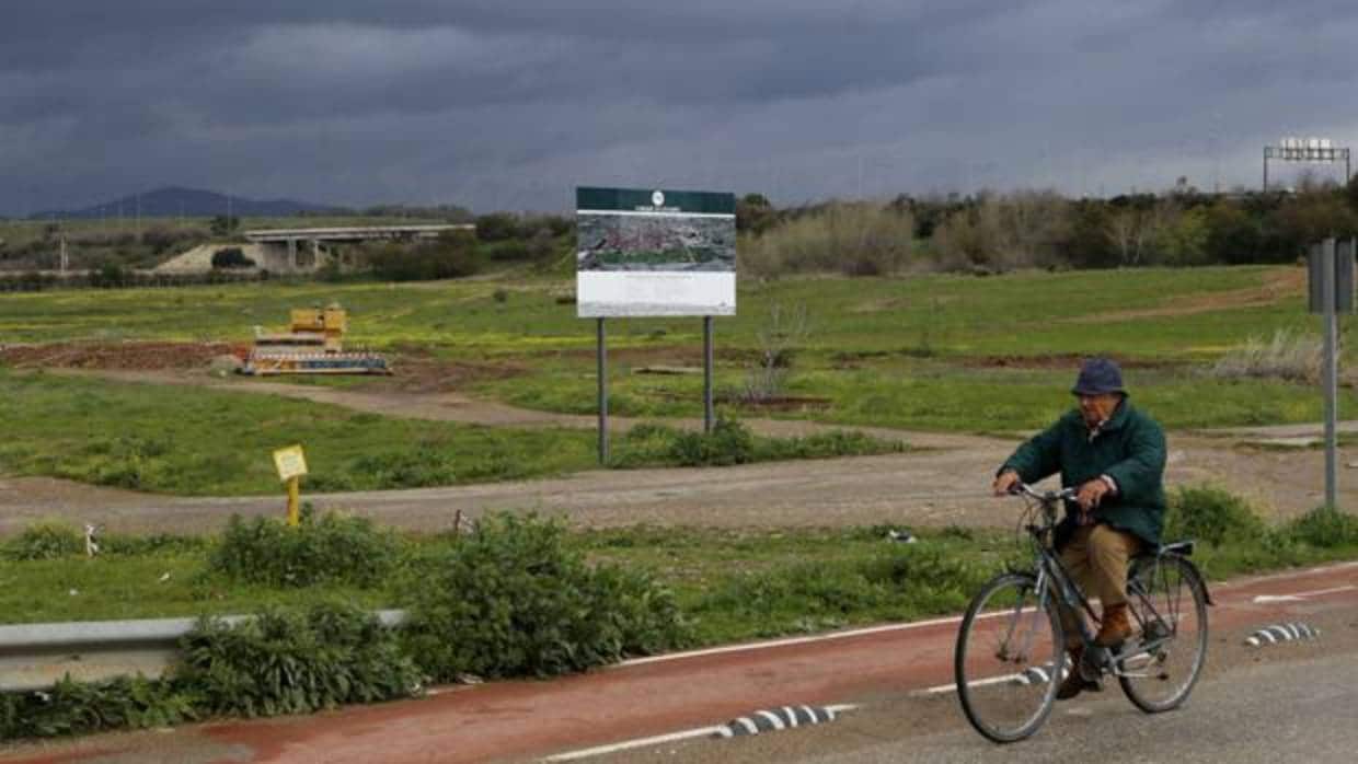 Un ciclista pasa junto al cartel que anuncia las obras del Parque de Levante