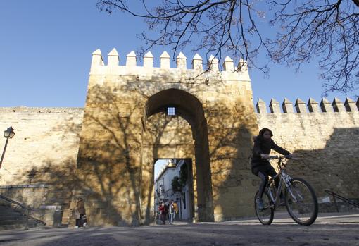 Una joven en bicicleta pasa por delante de la Puerta de Almodóvar