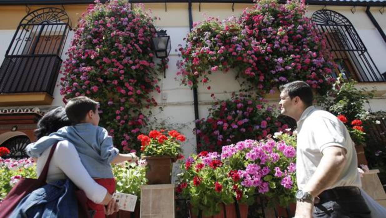 Una familia mira las flores de la casa que ha obtenido el primer premio