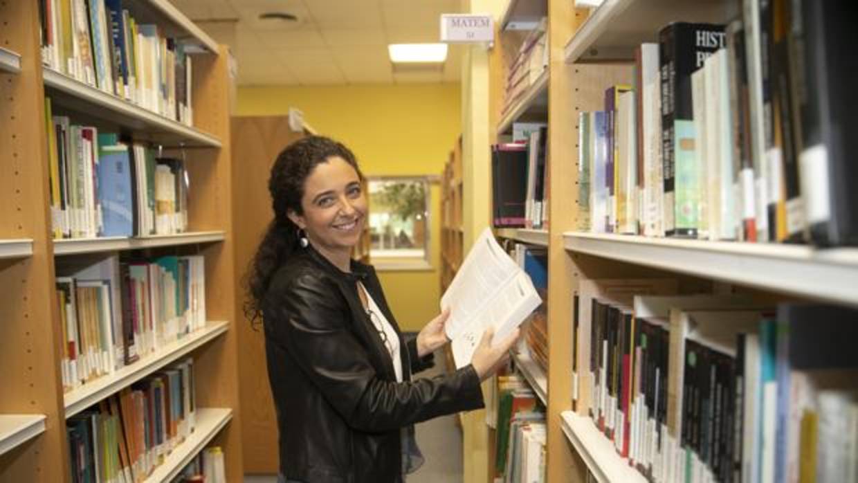 Bárbara Luque sostiene un libro en la biblioteca