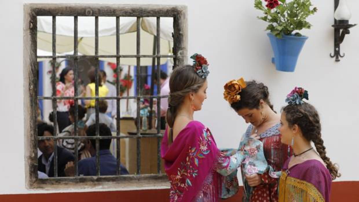 Una joven le coloca el mantoncillo a otra junto a una caseta