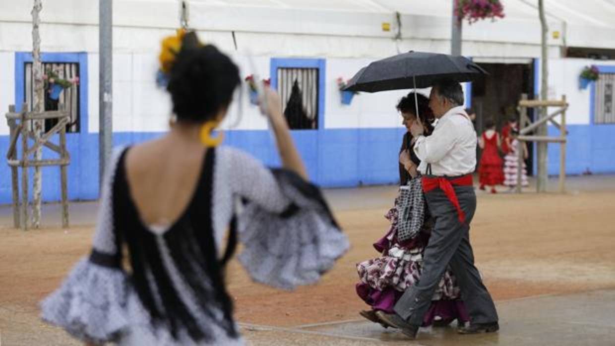 Una pareja camina por el recinto ferial de El Arenal bajo un paraguas este lunes