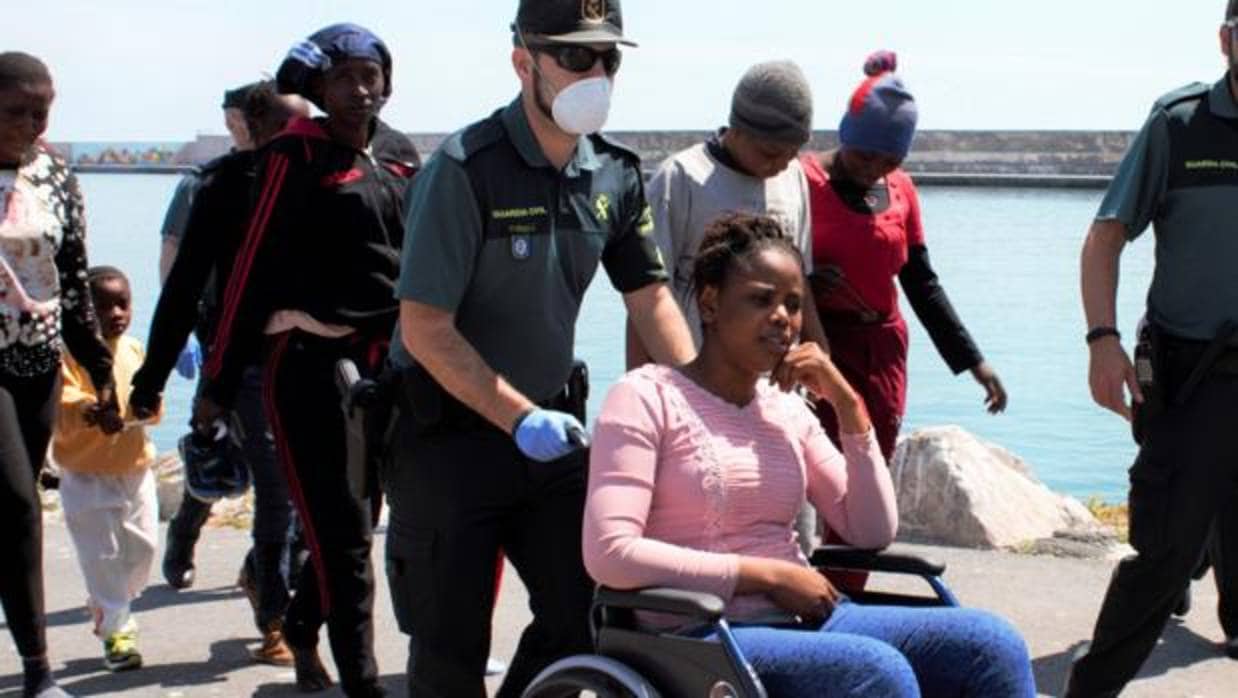 Un agente de la Guardia Civil traslada a una de las inmigrantes llegadas ayer