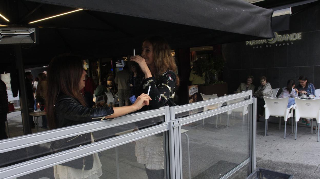 Dos jóvenes fuman en una terraza techada