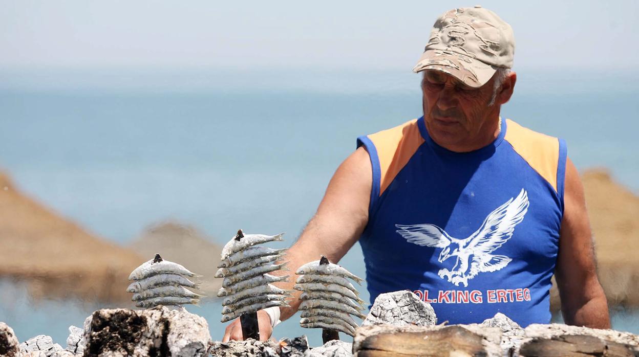 Un espetero asa unas sardinas en un chiringuito de la costa malagueña