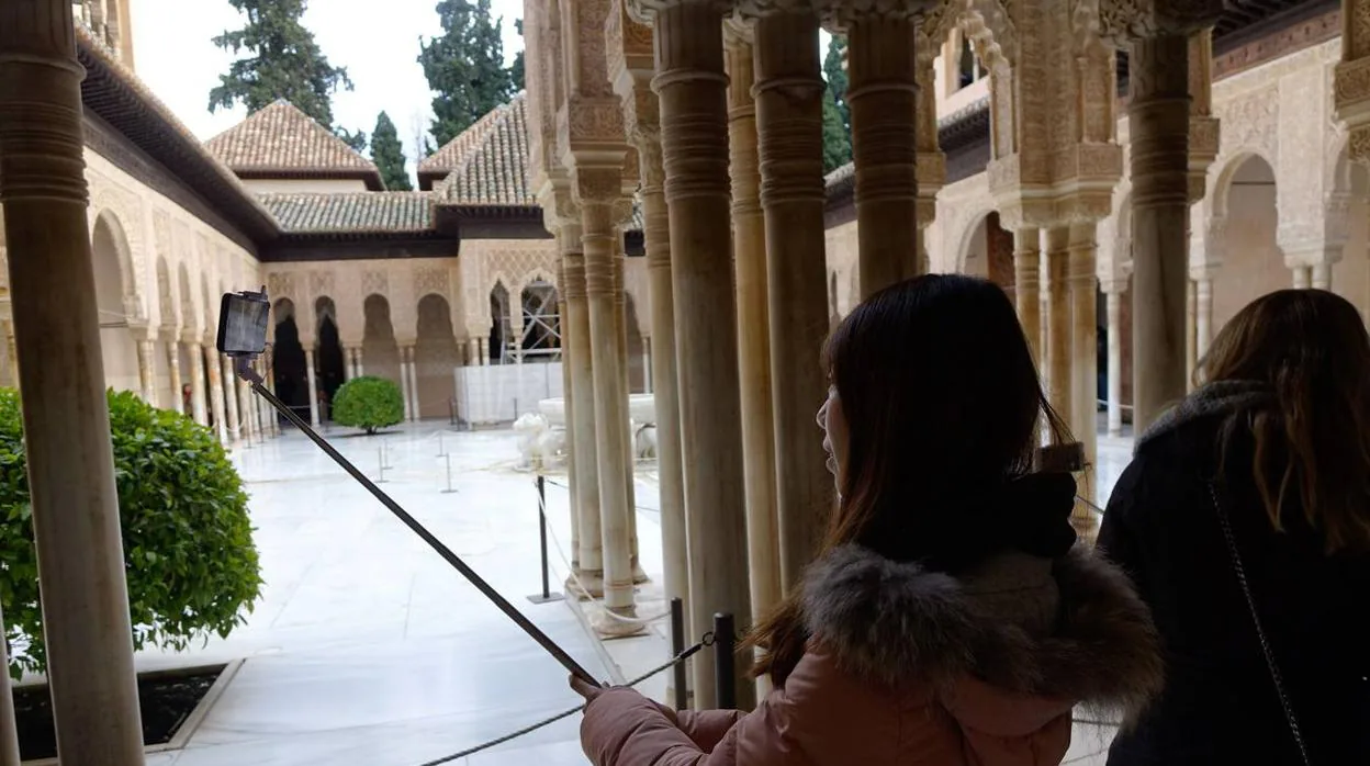 Una turista se hace una foto en el Patio de los Leones de la Alhambra, en Granada.