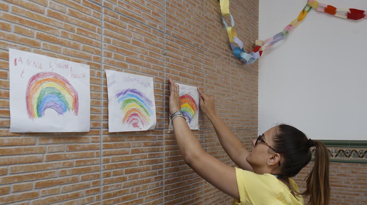 Una monitora cuelga los dibujos realizados por los niños del centro