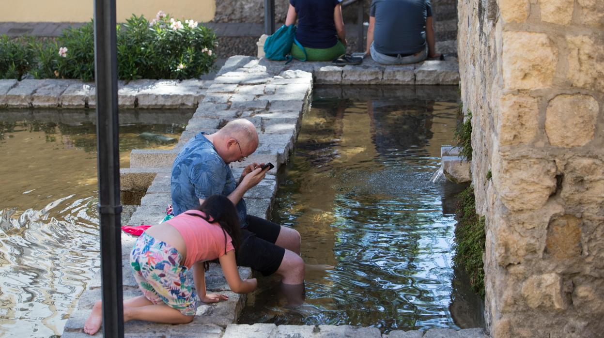 Dos ppersonas se refrescan en el estanque de la calle Cairuán, en Córdoba