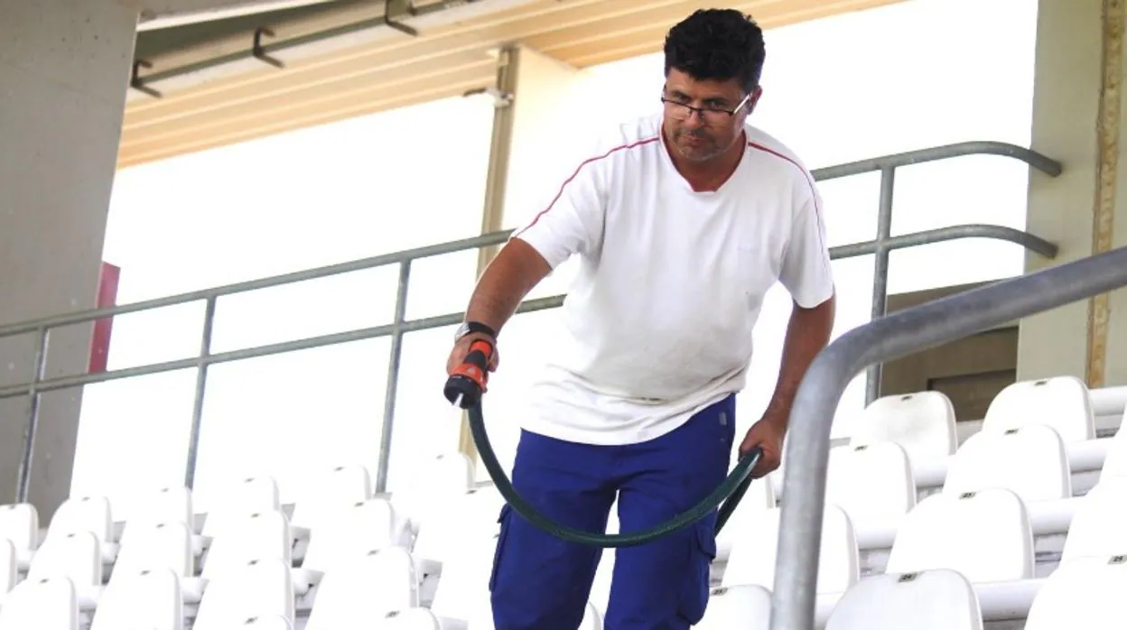Un trabajador limpia los asientos del estadio El Arcángel
