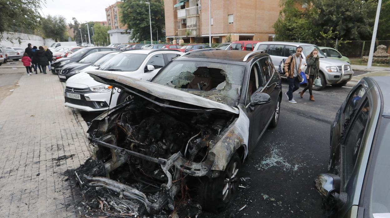 Dos personas se tapan la nariz por el olor a quemado ante dos coches dañados