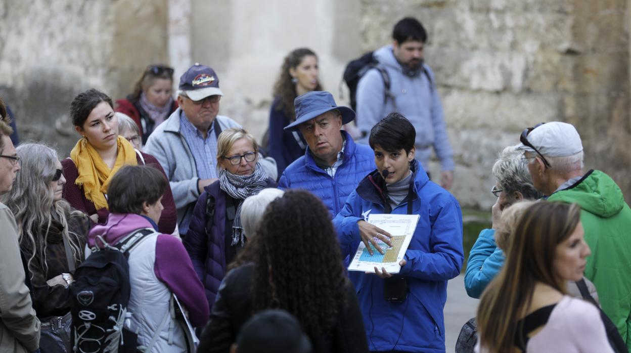 Una guía da explicaciones en el Patio de los Naranjos sobre la Mezquita-Catedral a un grupo de turistas