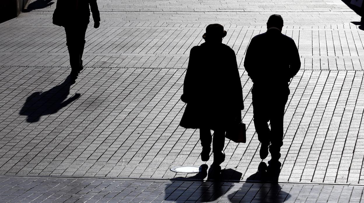 Dos personas cruzan por la Puerta del Puente de Córdoba en un día de sol y frío