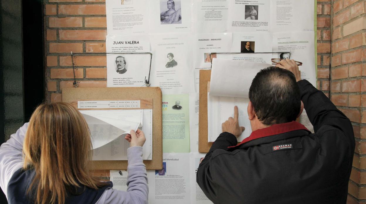 Dos ciudadanos miran las listas en el colegio electoral del IES Medina Azahara