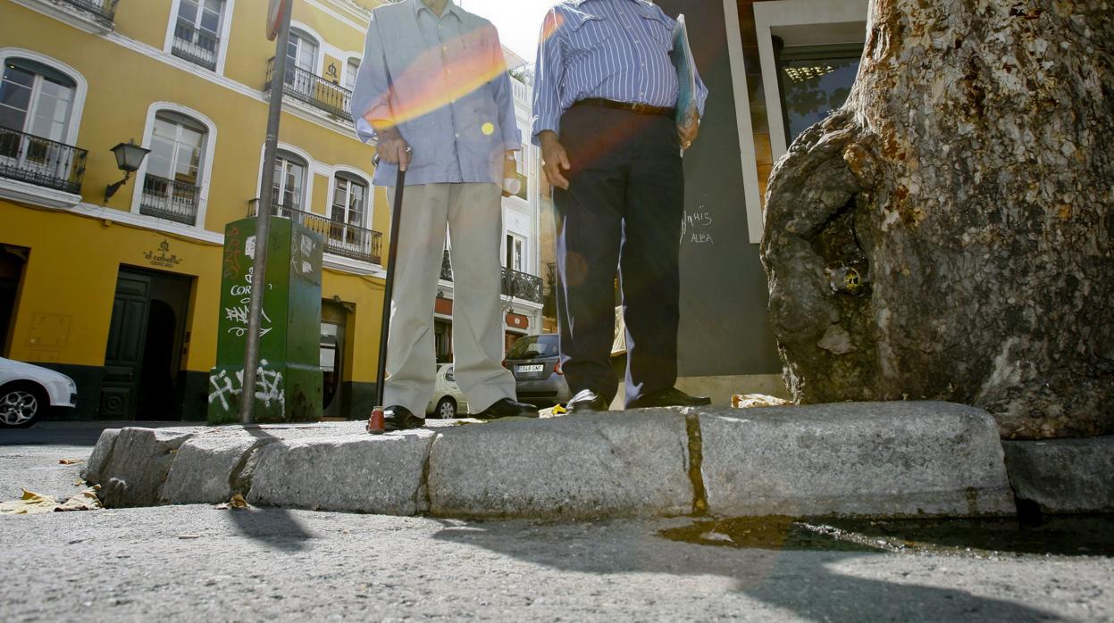 Dos personas mayores se detienen ante un bordillo no rebajado