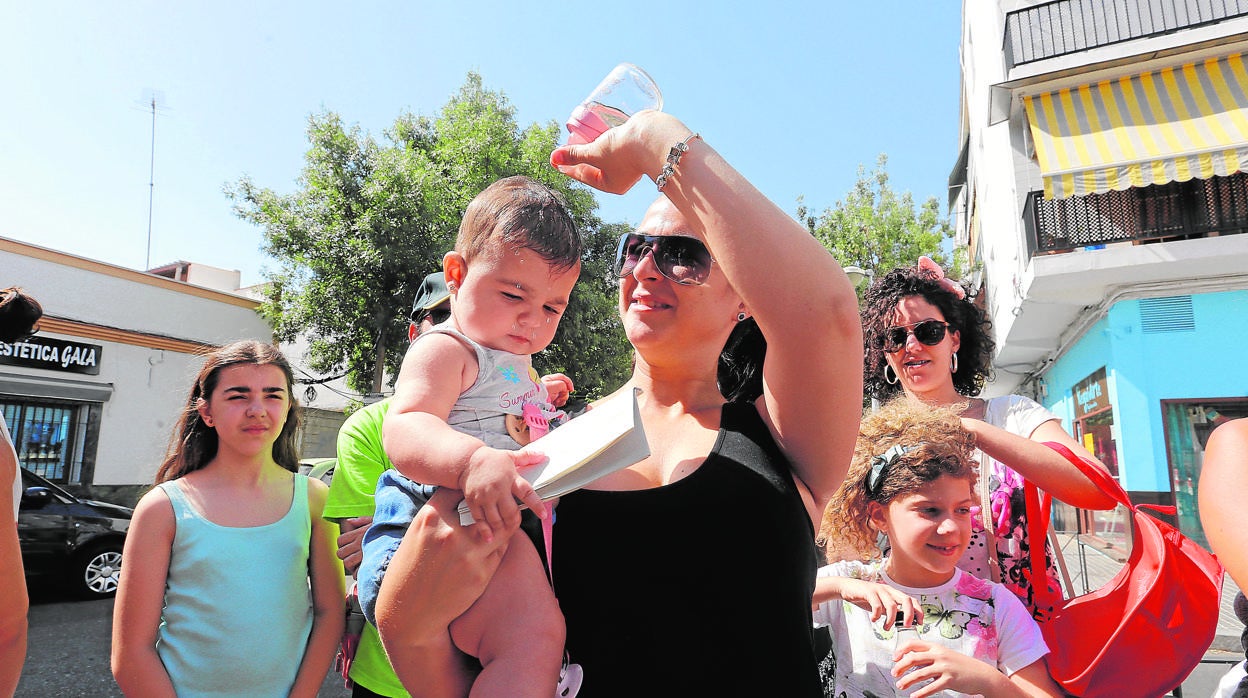 Una mujer refresca a un bebé a la salida de un colegio