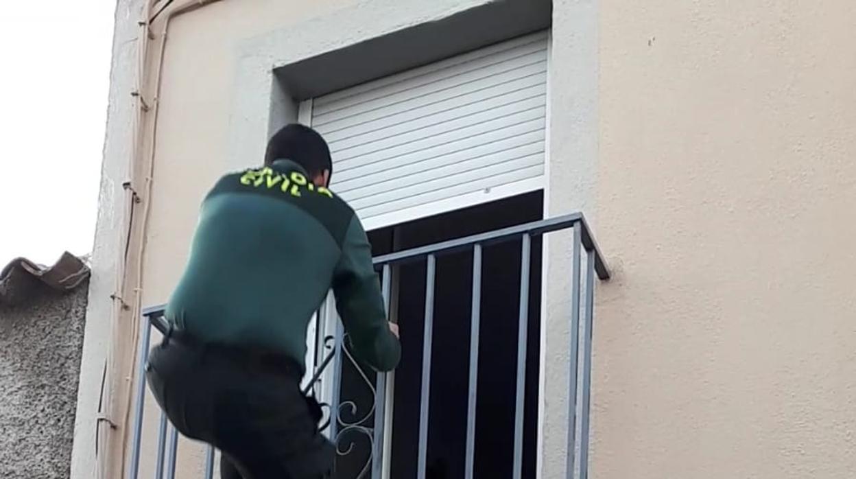 Un agente escala la fachada para acceder al interior de la vivienda