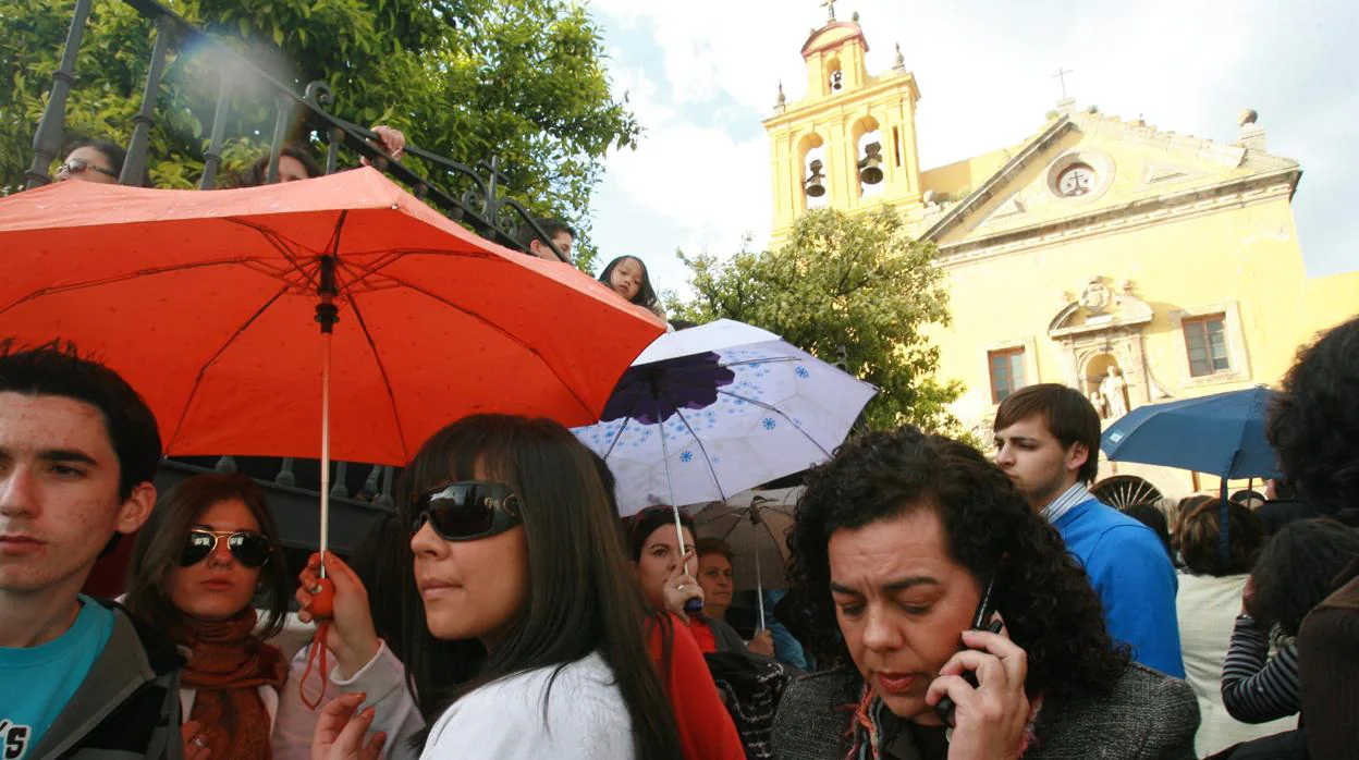 La gente espera bajo los paraguas la salida de la cofradía del Caído en la tarde del Jueves Santo en Córdoba