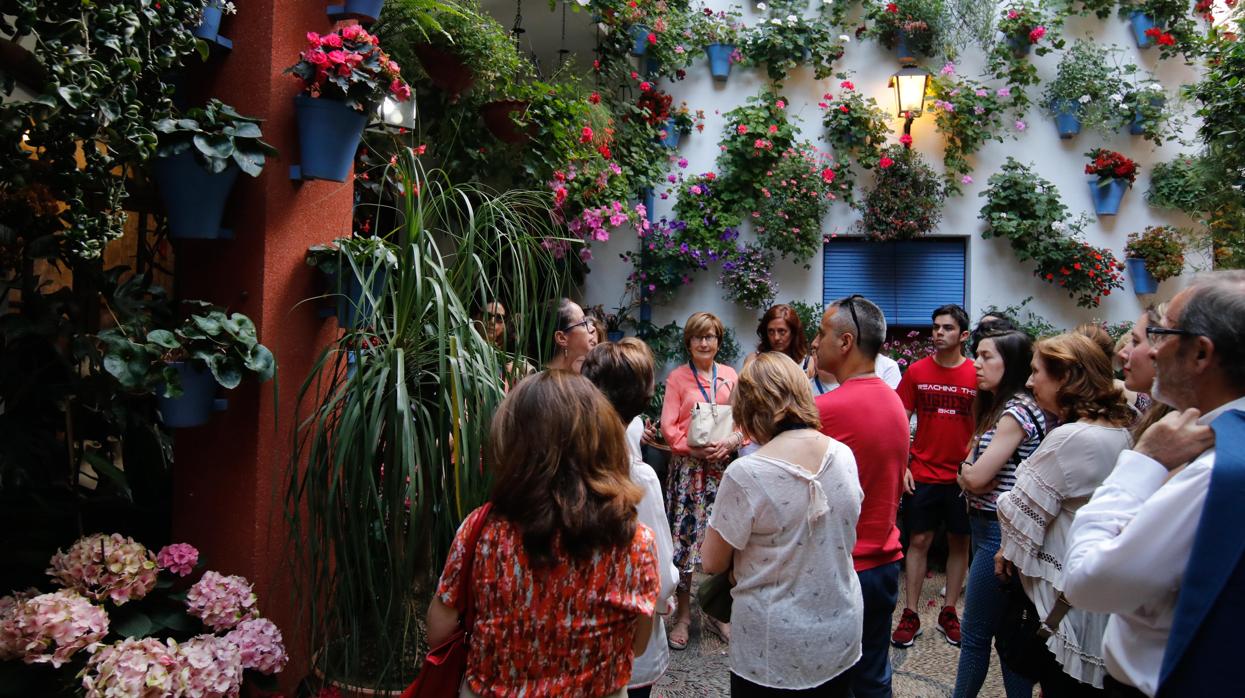 Visitantes de una ruta en el patio de la calle Martín de Roa, 2 oyen atentamente a su guía