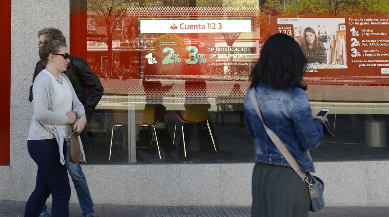 Varias personas pasan delante de una oficina del Banco Santander