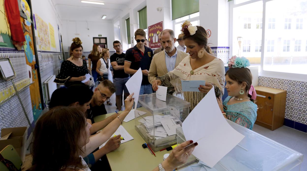 Una mujer vestida de gitana introduce su voto en un colegio electoral de Córdoba