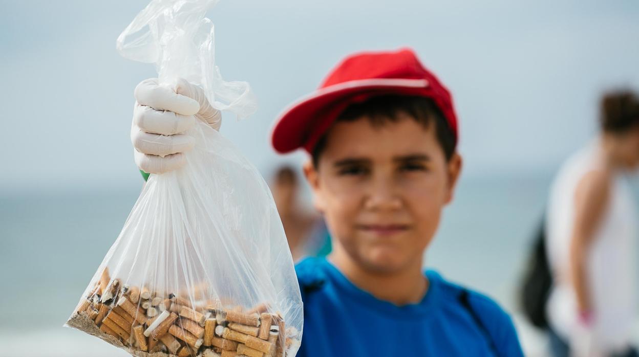 Un niño sostiene colillas en una campaña de limpieza de playas en Andalucía