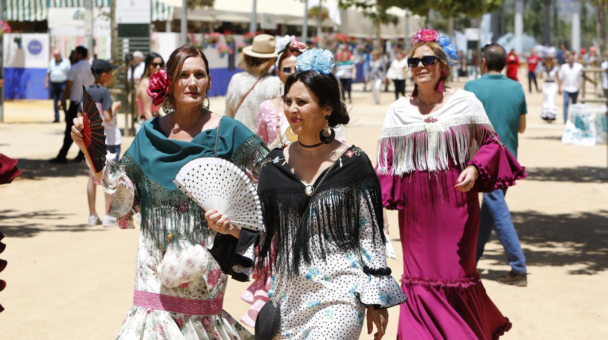 Dos mujeres pasean por el ferial sin separarse de sus abanicos