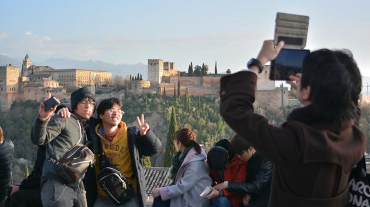 Unos turistas asiáticos se fotografían frente a la Alhambra, en Granada