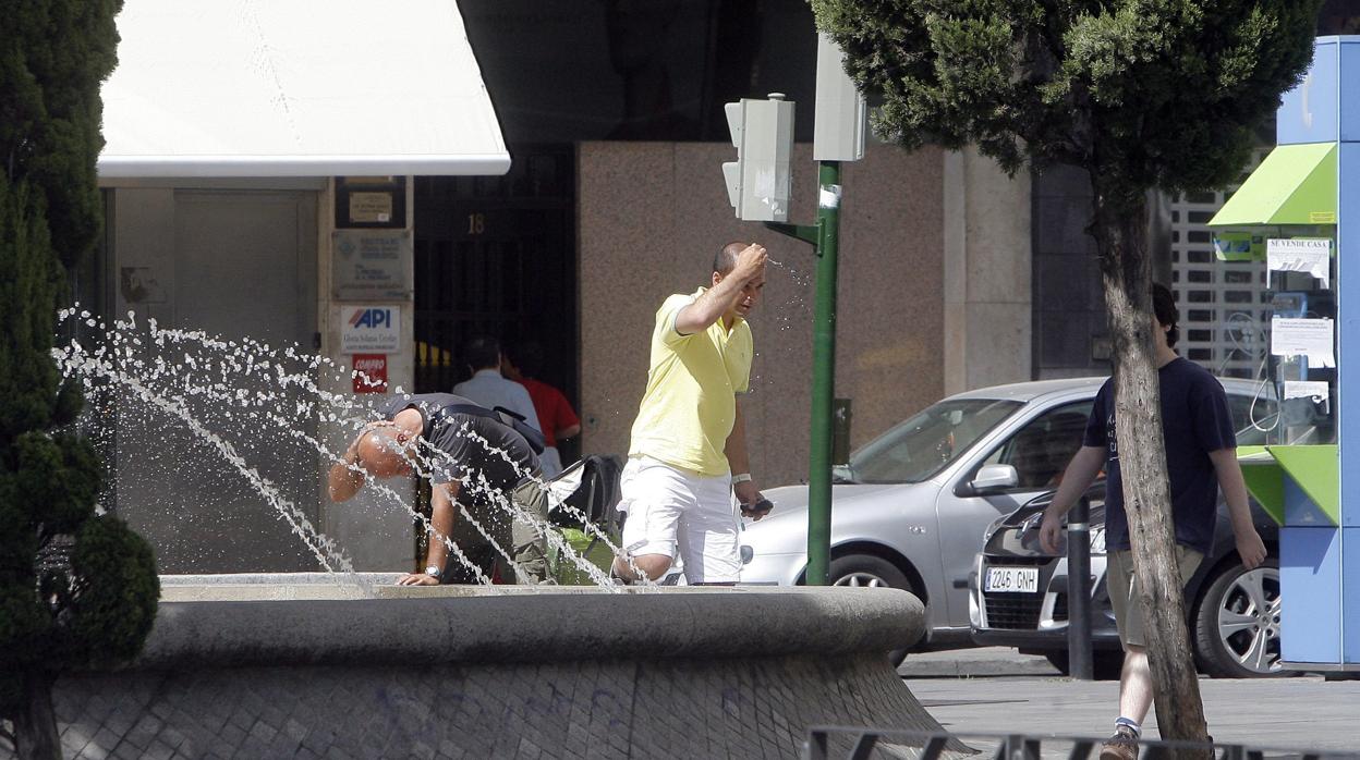 Dos hombres se refrescan en la fuente de las Tendillas