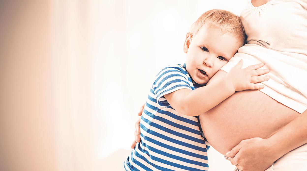 Un niño abraza a su madre, embarazada