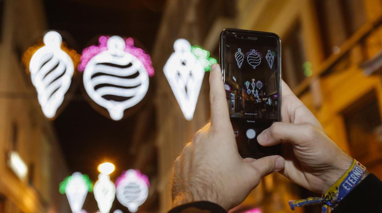 Un hombre fotografía el alumbrado navideño de una calle comercial de Córdoba