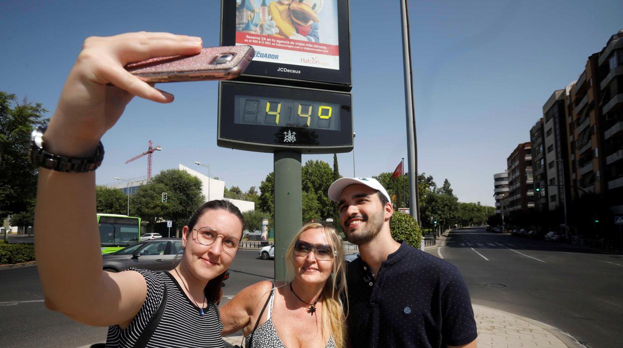 Un selfie de unos turistas frente a un termómetro de la calle en Córdoba