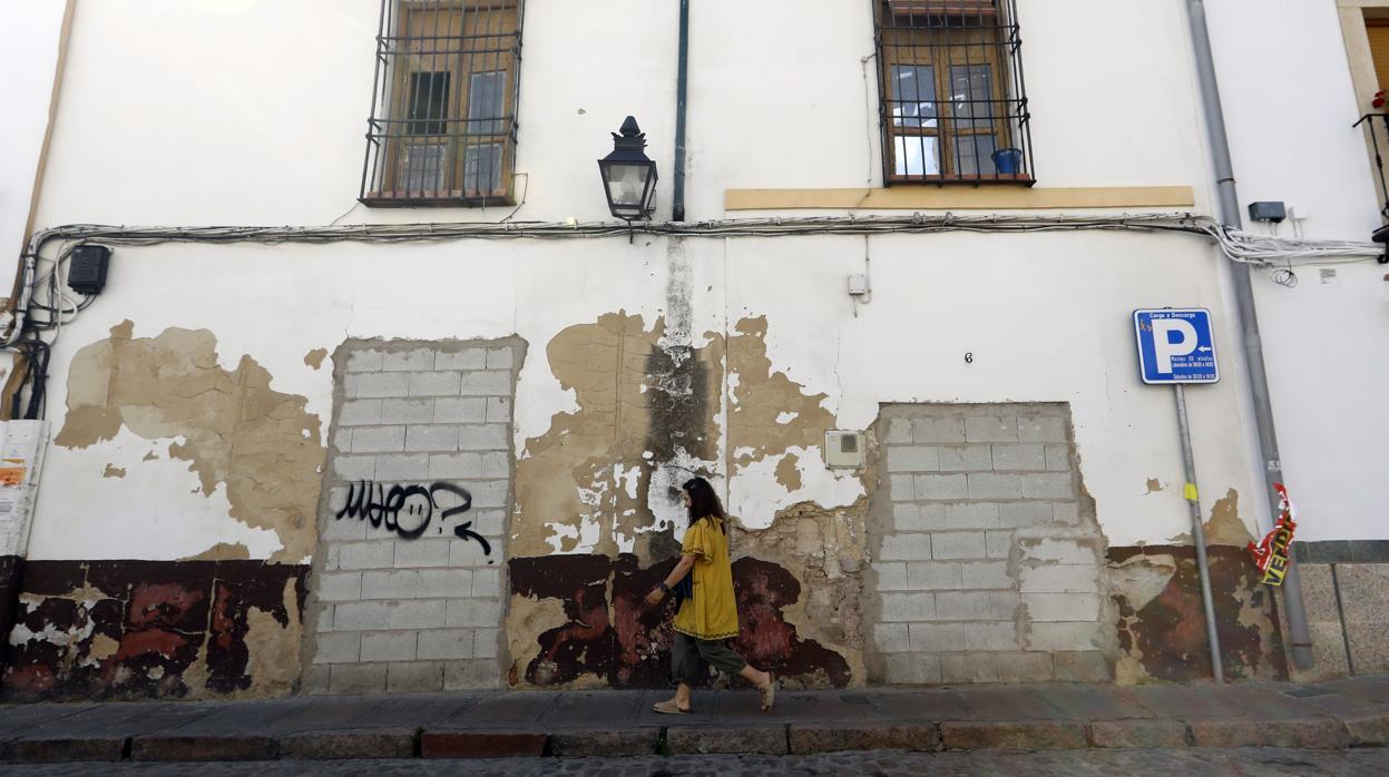 Una vecina pasa frente a una vivienda abandonada en San Agustín