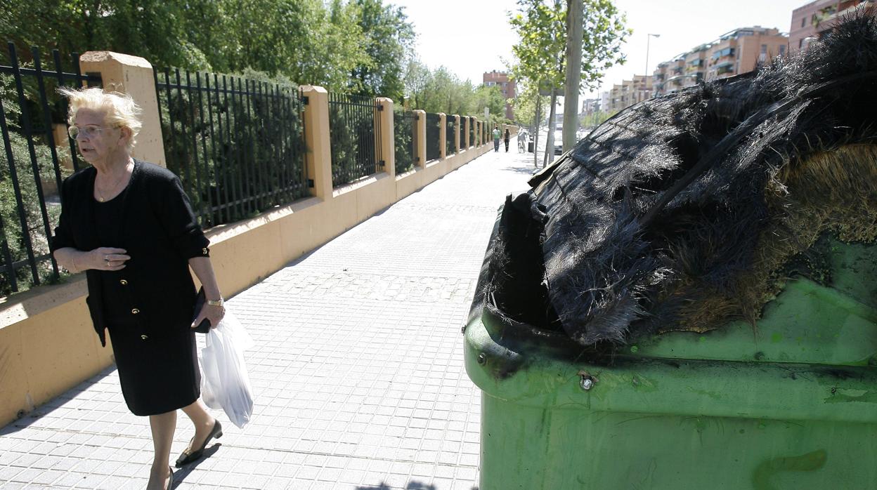 Una mujer pasa junto a un contenedor de Sadeco quemado