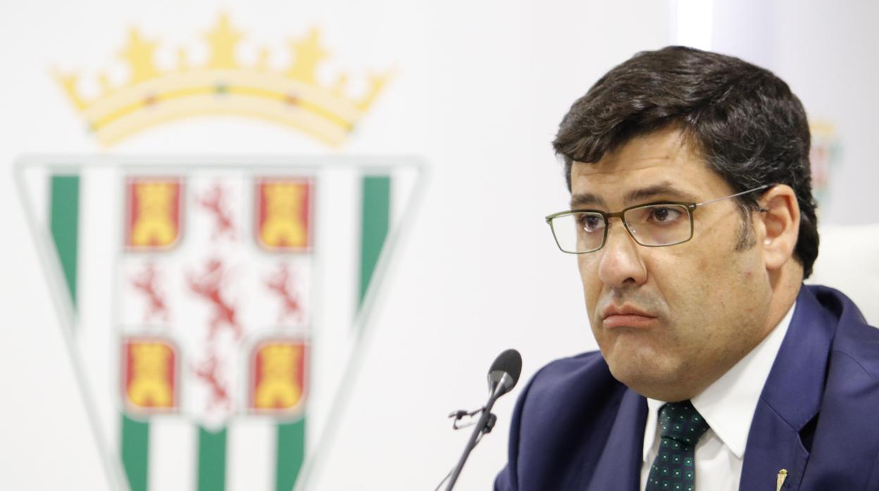 El presidente del Córdoba, Jesús León, junto al escudo del club