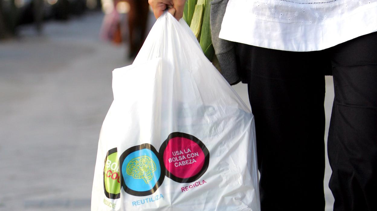 Una señora sale de la compra con una bolsa de plástico de un solo uso