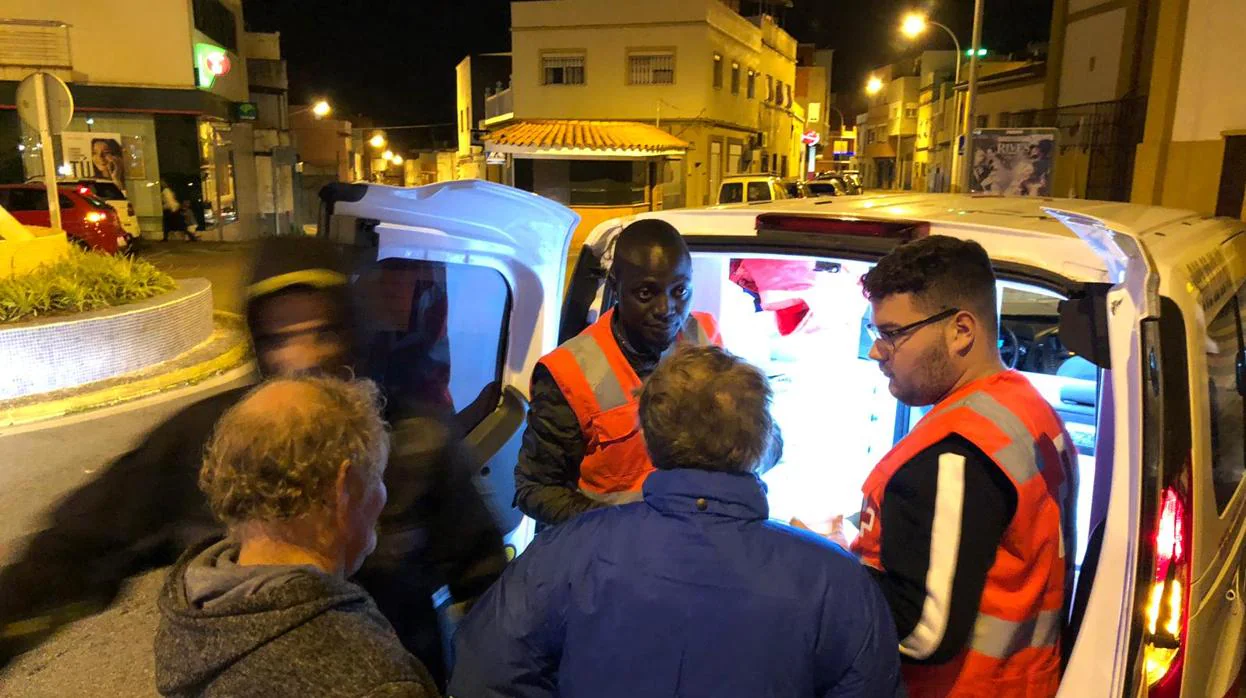 Voluntarios de la Cruz Roja de Algeciras entregan alimentos a varias personas sin hogar