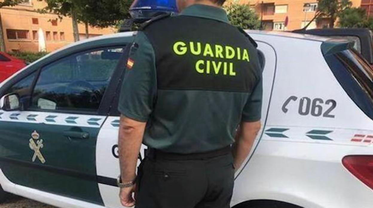 Un agente de la Guardia Civil junto a un vehículo oficial