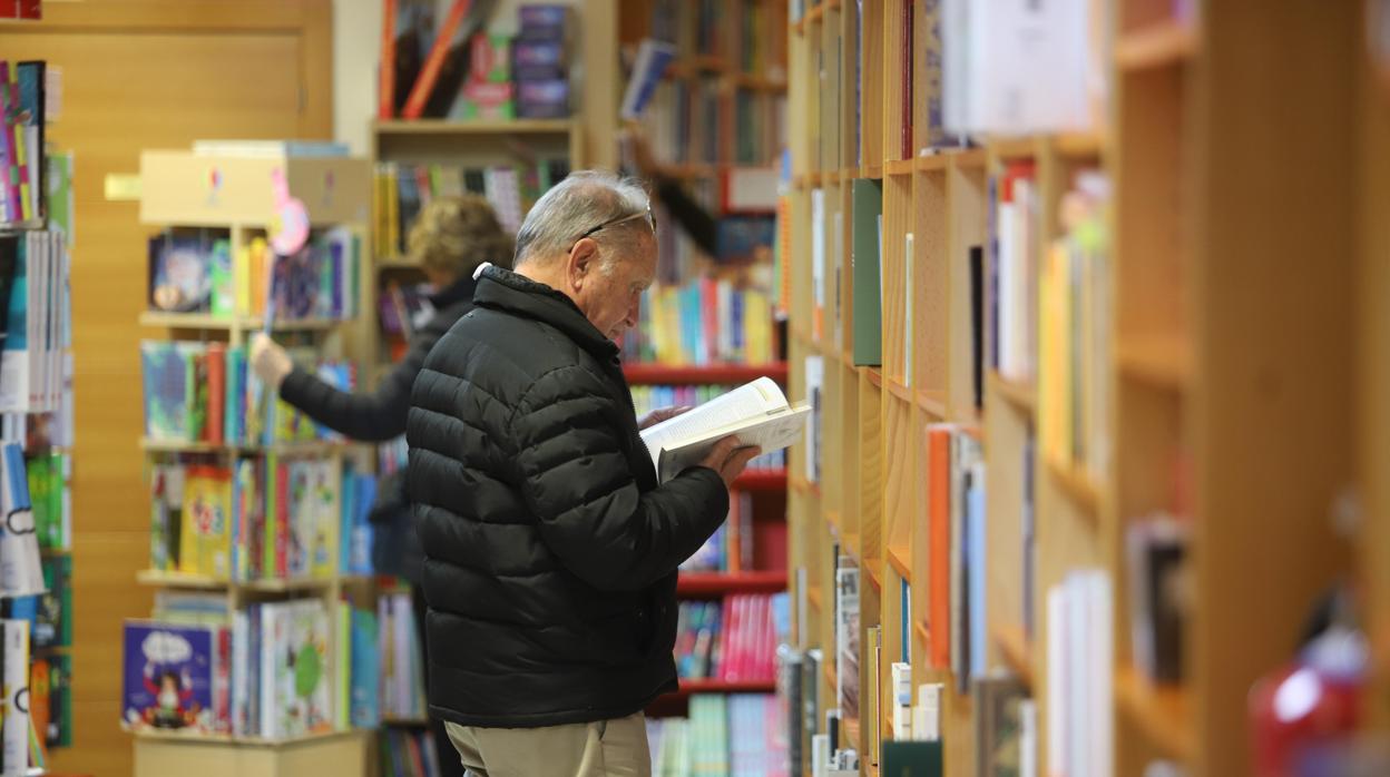 Un hombre consulta un libro de la estantería en la Librería Luque