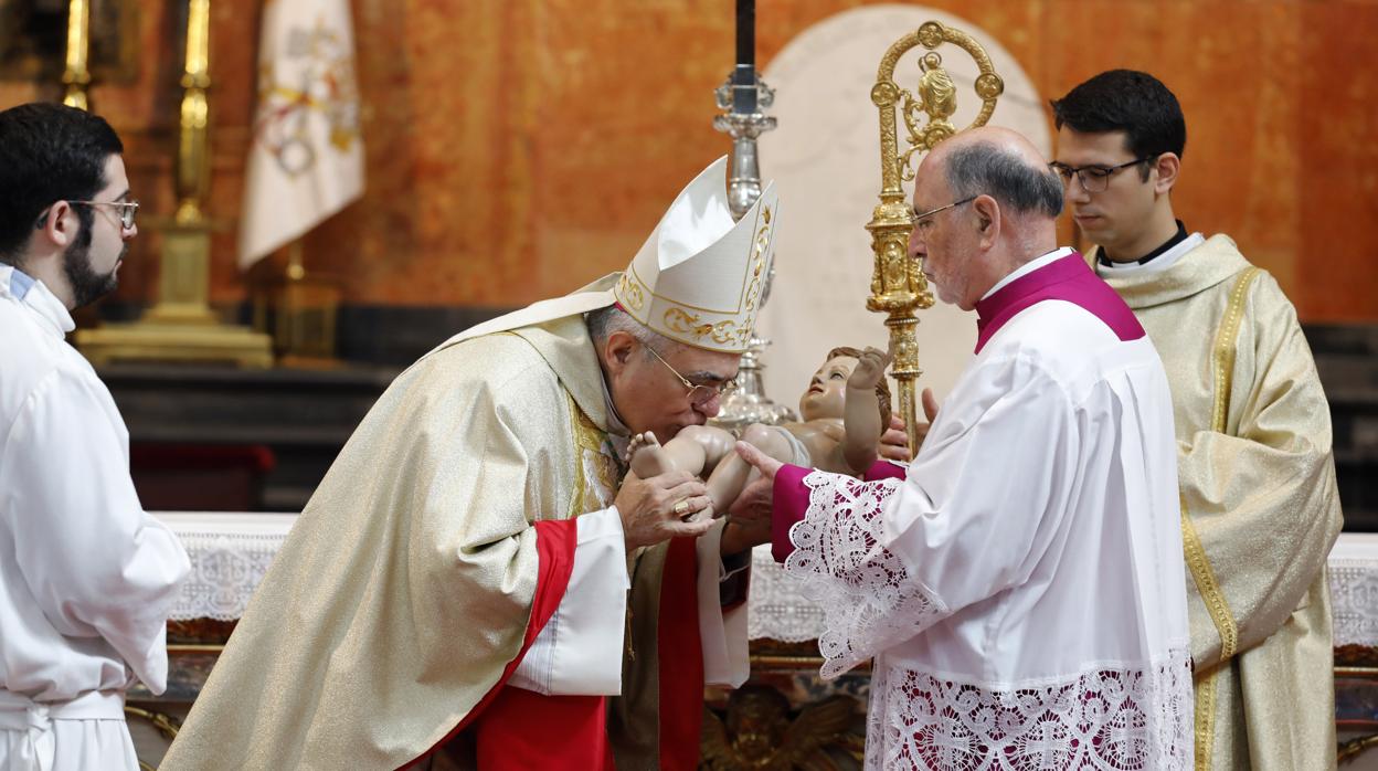 El obispo de Córdoba besa la imagen del niño Jesús tras la misa